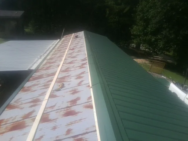 Old rusted panels beside newly installed green metal roofing — Wind Damage Roof Repair by Roofing Brothers in Prior Lake