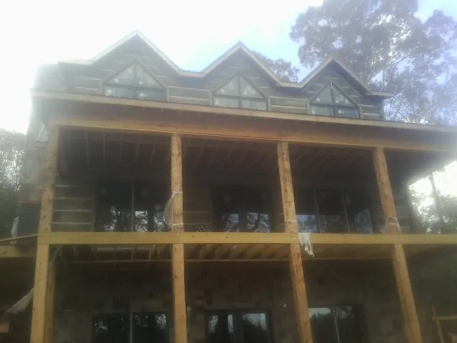 Dormers and porch framing on a large log home under construction — Roof Coating work by our crew in Prior Lake