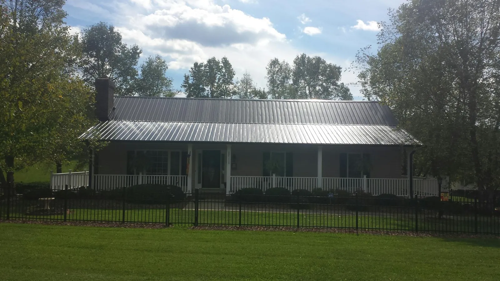 Gray metal roof on a brick ranch with a full width front porch — Gutter Guard Installation work by our crew in Prior Lake