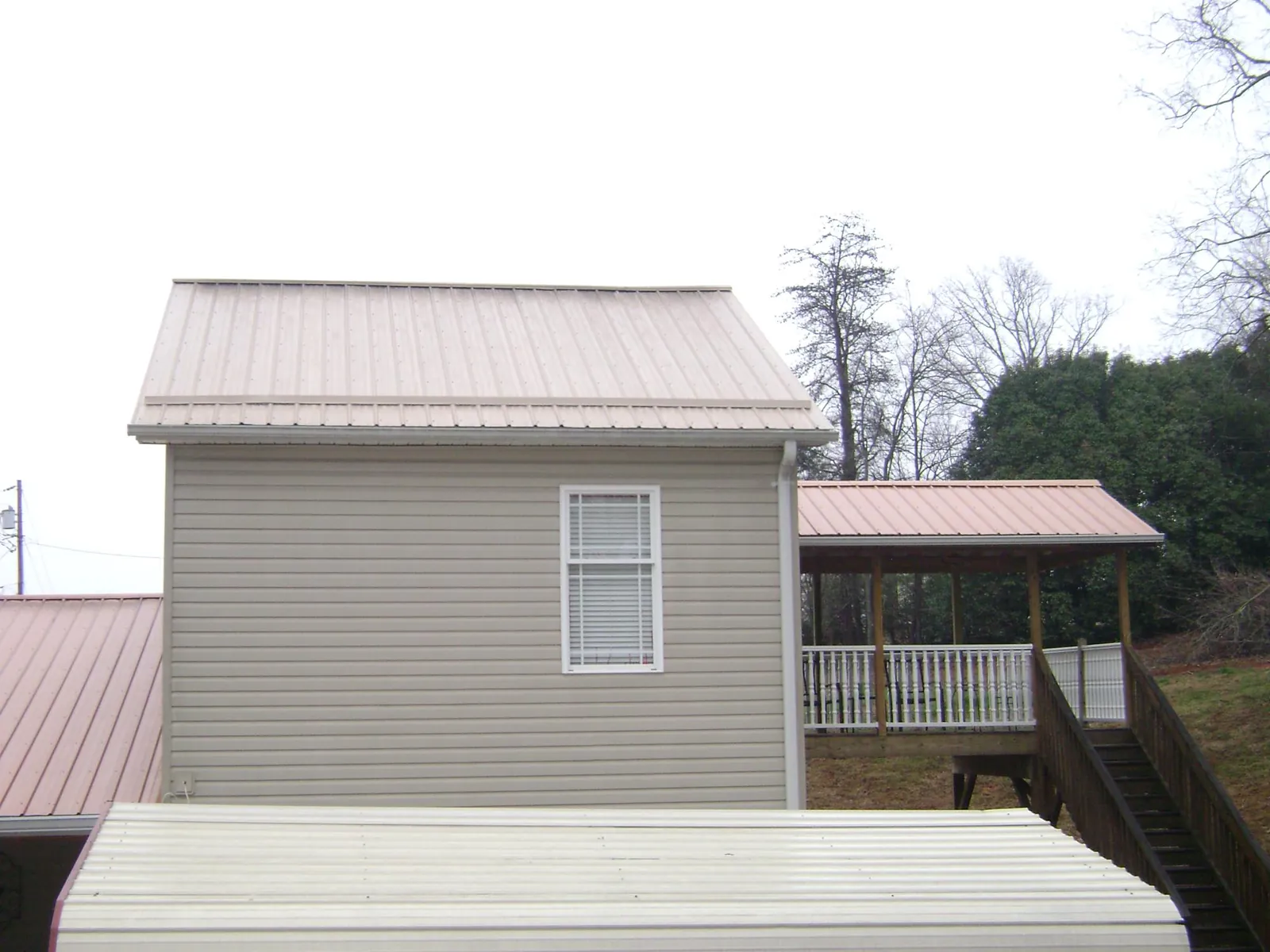 Tan metal roofs on a two story addition and attached porch, from a Roof Replacement job in Prior Lake