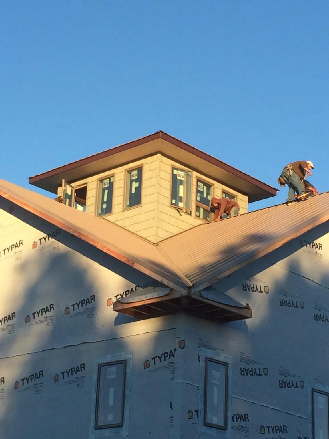 Roofers working around a rooftop cupola on a new metal roof at sunset — Roof Waterproofing in Prior Lake by Roofing Brothers